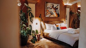 A well-lit bedroom with a large bed, a painting on the wall, and potted plants. - Rittergut Positz GmbH (Oppurg)