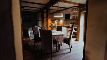 A dining area with a round table, wicker chairs, and a hanging light fixture.
