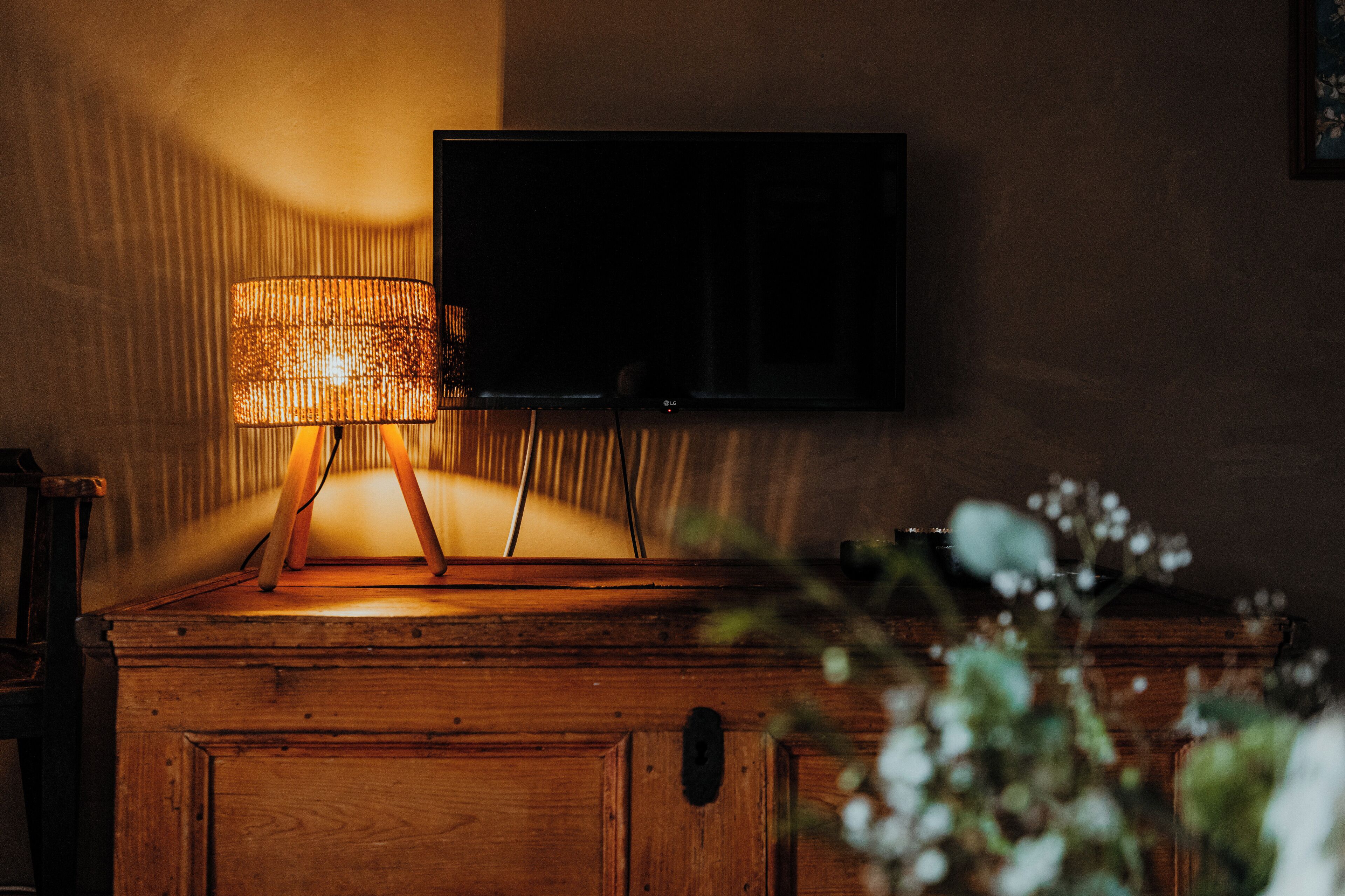 Een houten kast met daarboven een televisie aan de muur.