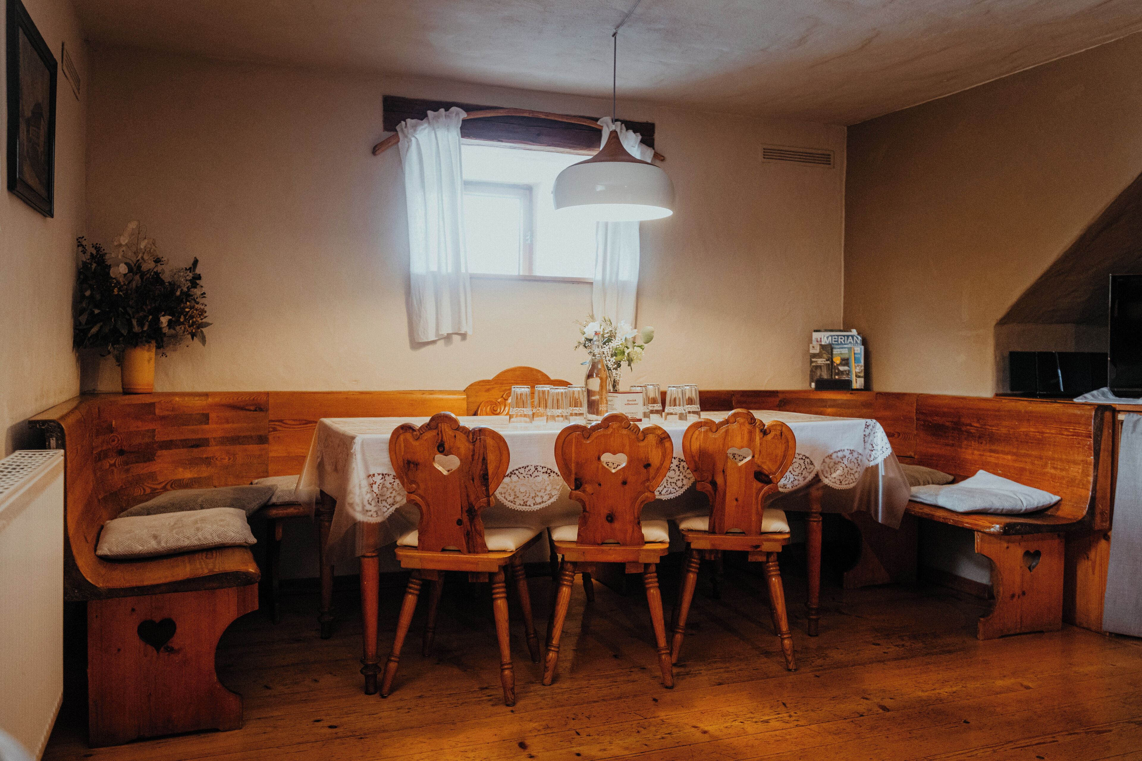 Een eethoek met een houten bank en stoelen rond een tafel voor vier personen.