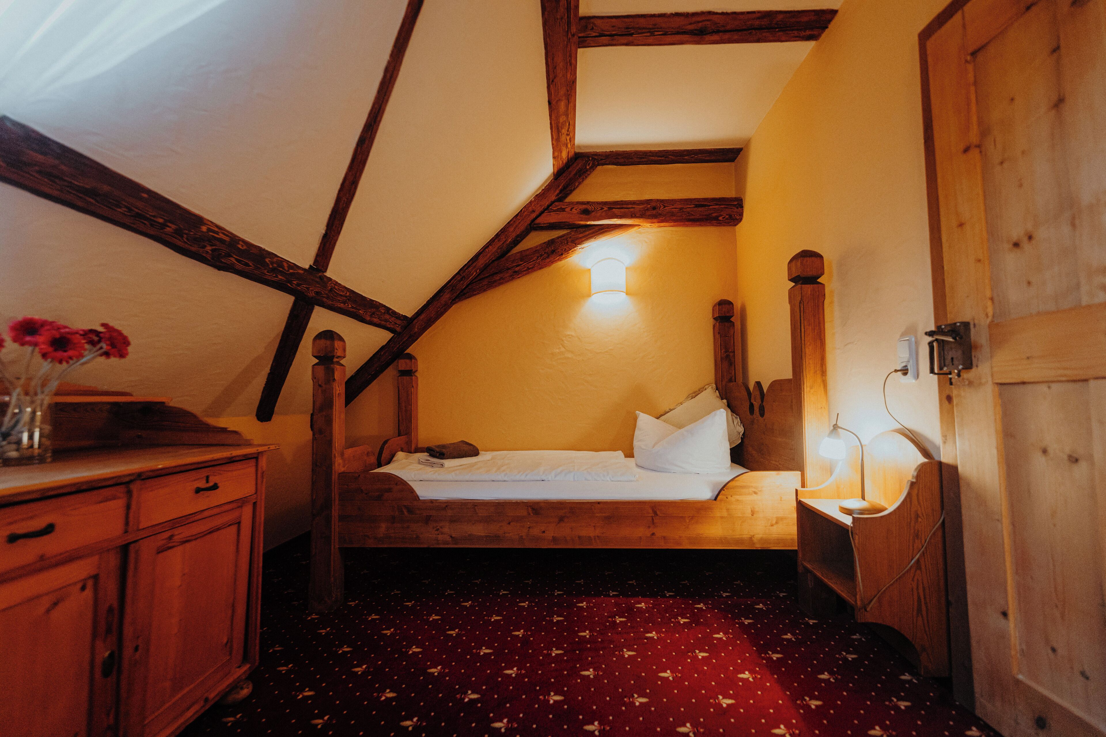 A bedroom with a wooden bed, a nightstand, a bedside lamp, and a wooden wardrobe.