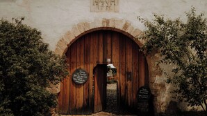 An arched wooden door with a plaque above it and two signs on either side. - Rittergut Positz GmbH (Oppurg)
