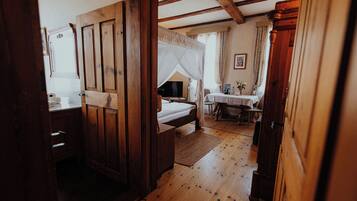 A wooden-floored bedroom with a bed, a bedside table, and a television.