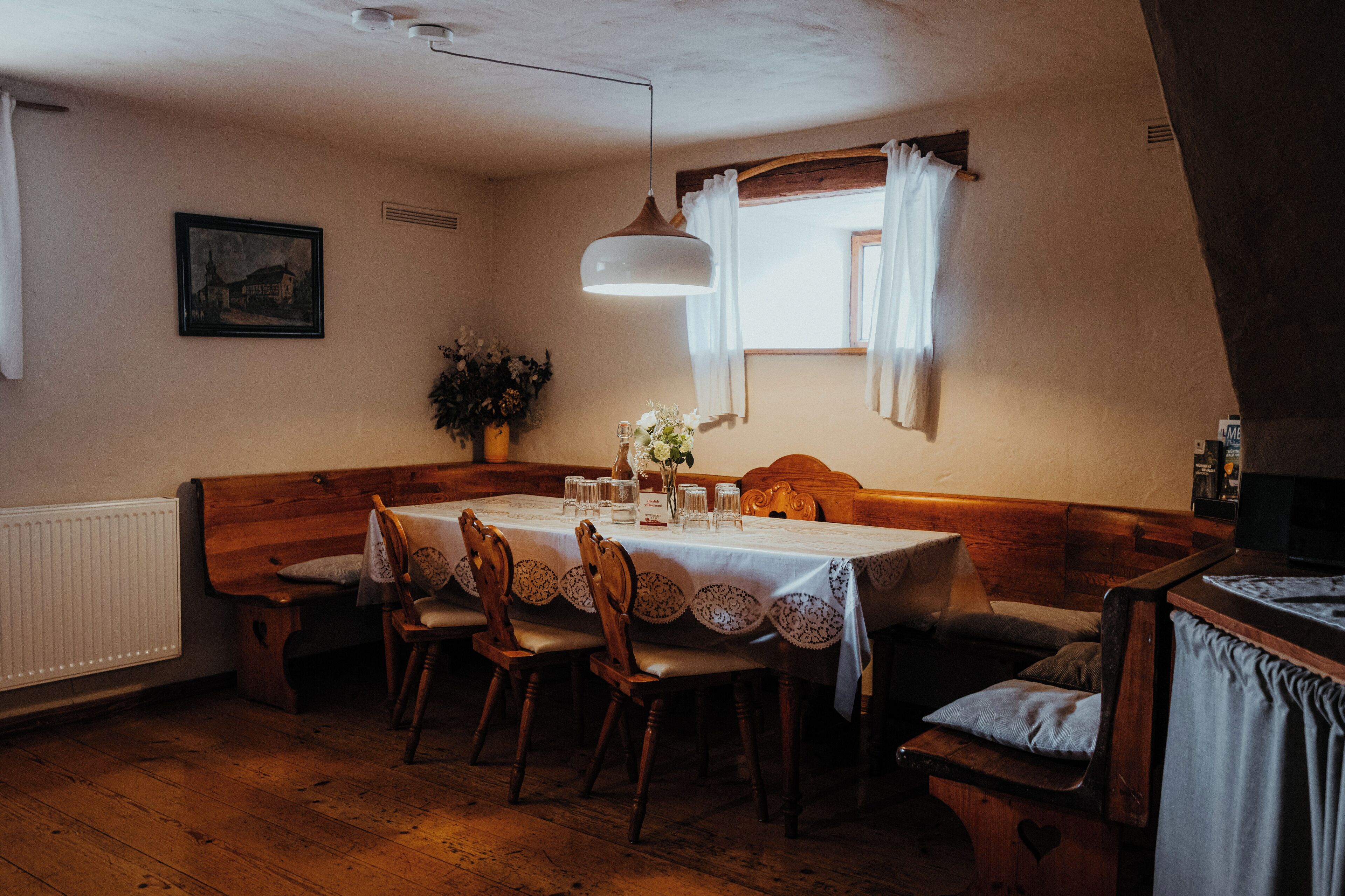 A dining area with a wooden table set for four, surrounded by wooden chairs.