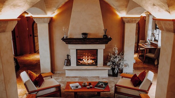 A cozy lounge area with a fireplace, comfortable seating, and a table with books and a teapot. - Rittergut Positz GmbH (Oppurg)