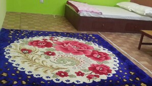 A room with a bed, a wooden bench, and a floral-patterned rug. - Tamang Homestay (Dhulikhel)