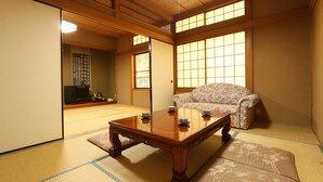 Et traditionelt japansk rum med tatamimåtter, et lavt træbord, en sofa og skydedøre.