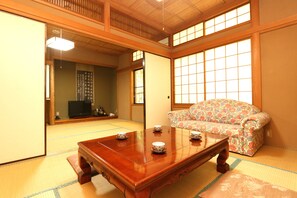 A traditional Japanese room with tatami flooring, a low wooden table with cups, a sofa with floral upholstery, and sliding doors. - Ajiwainokokoro Kintokisan-so (Hakone)