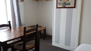Une chambre d’hôtel comprenant une table à manger en bois, deux chaises, un lit, une armoire et un tableau d’affichage fixé au mur.