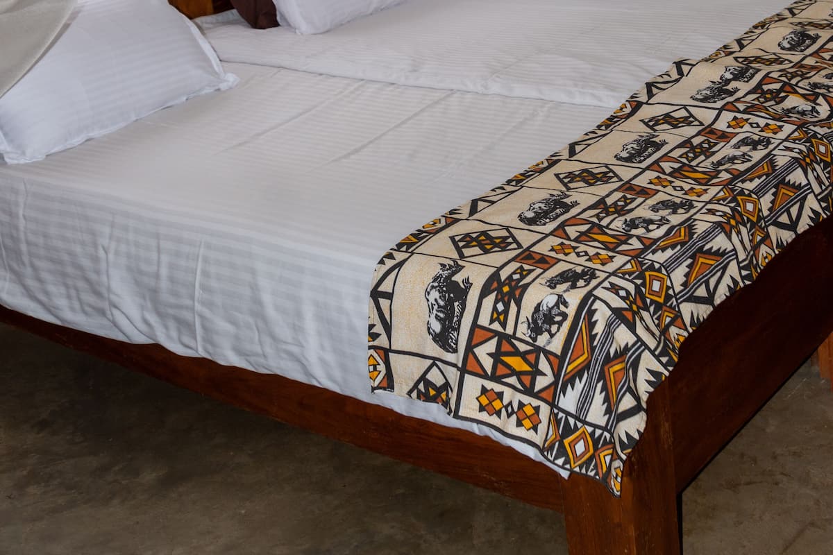 A bed with a canopy, white bedding, and a patterned throw.