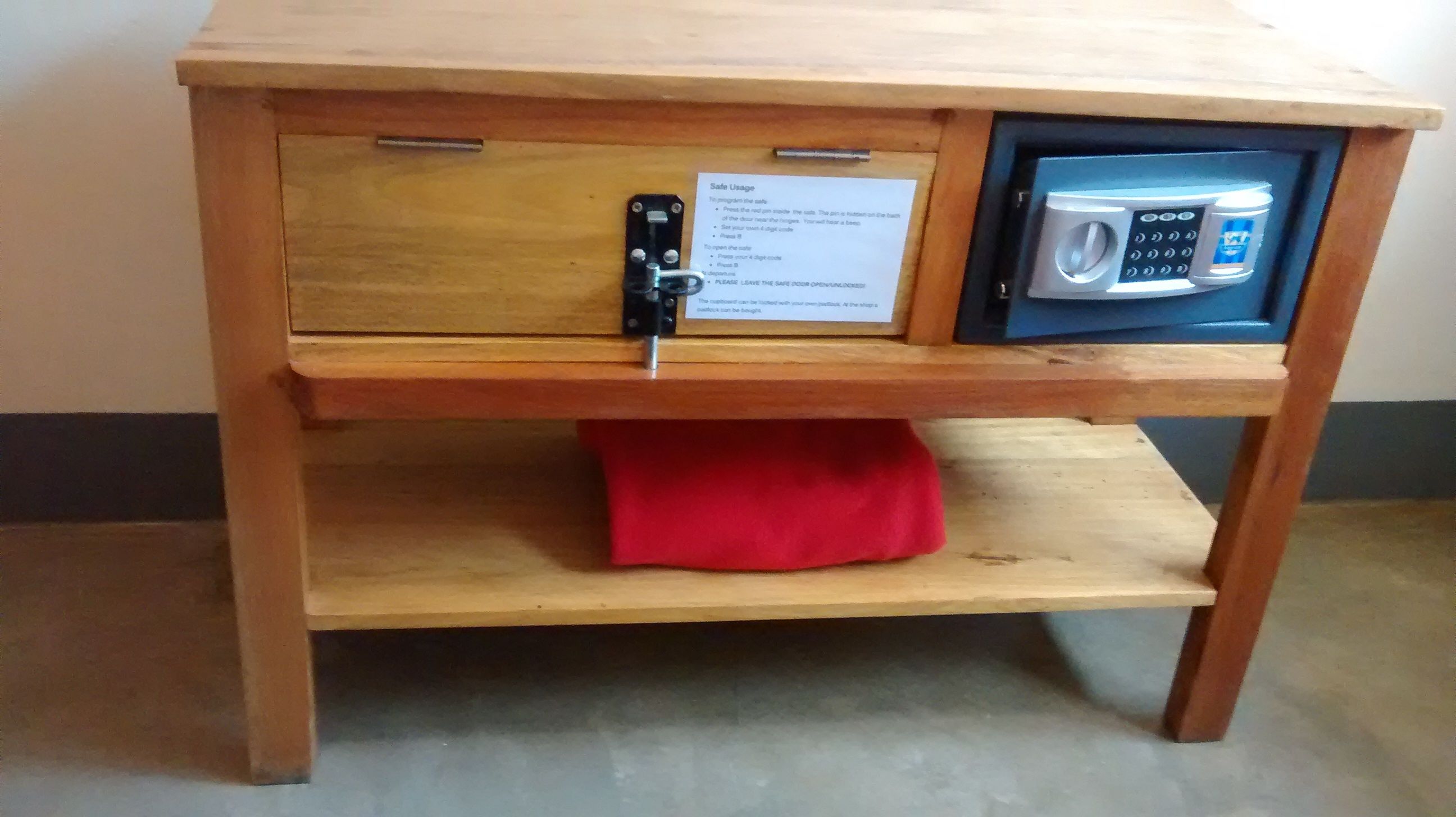 A wooden table with a built-in safe and a microwave.