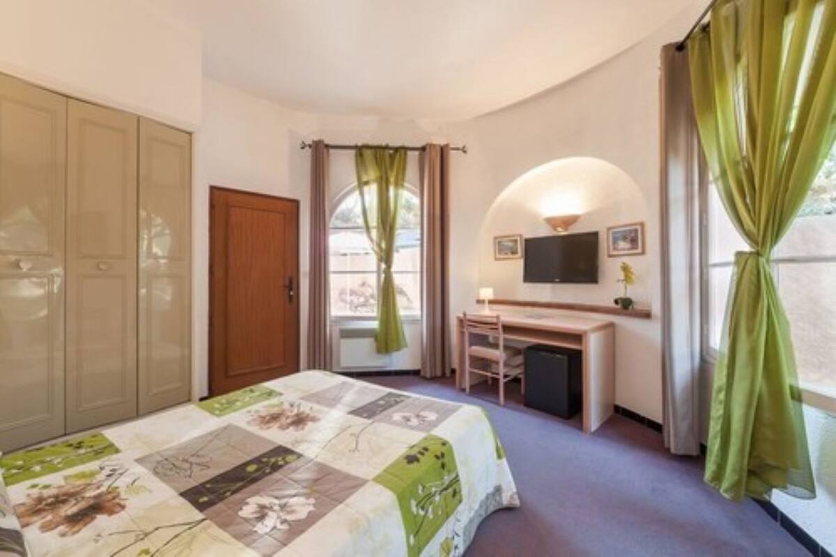 Un dormitorio con cama, escritorio, silla, televisor y armario.
