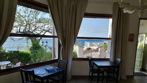 Habitació amb vista al mar, una taula amb cadires i una finestra amb cortines.