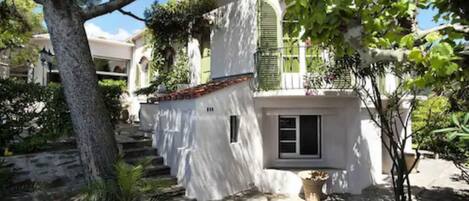 Un edificio blanco con techo de tejas rojas, un pequeño balcón y una puerta con ventana.