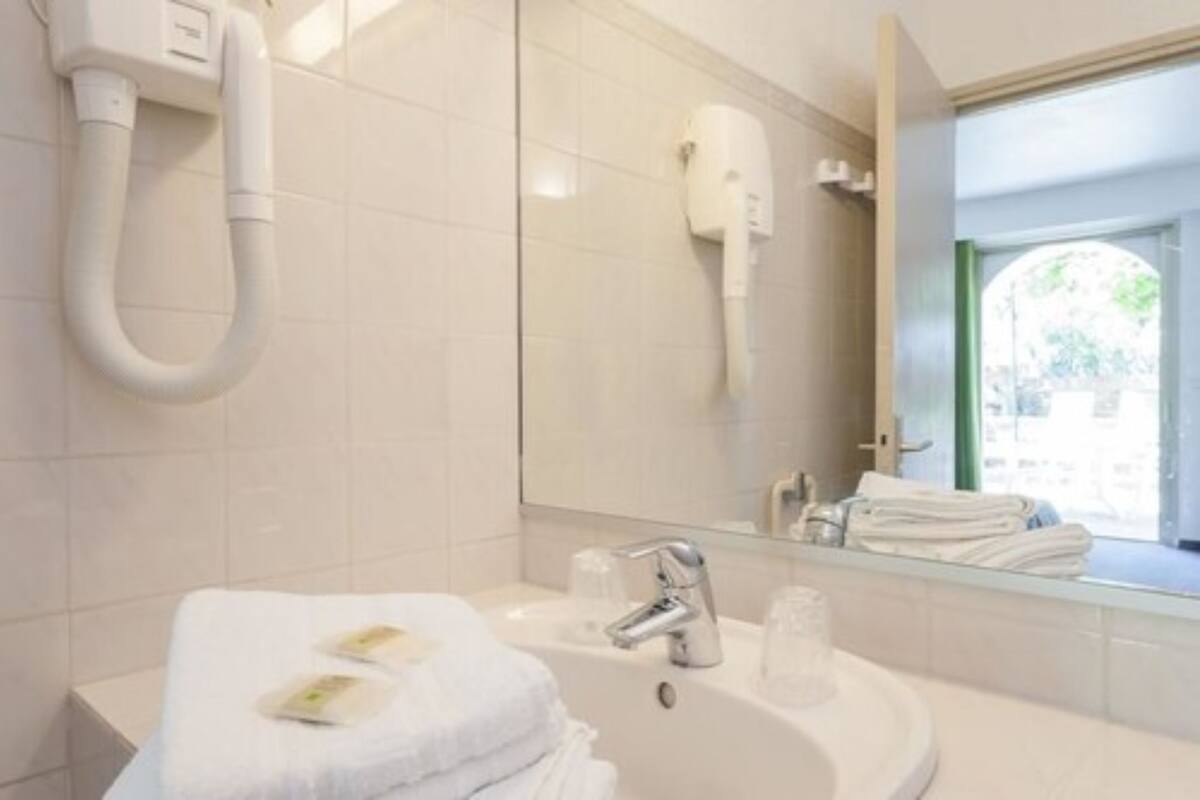 Un baño con lavabo, espejo, toallero y secador de pelo montado en la pared.