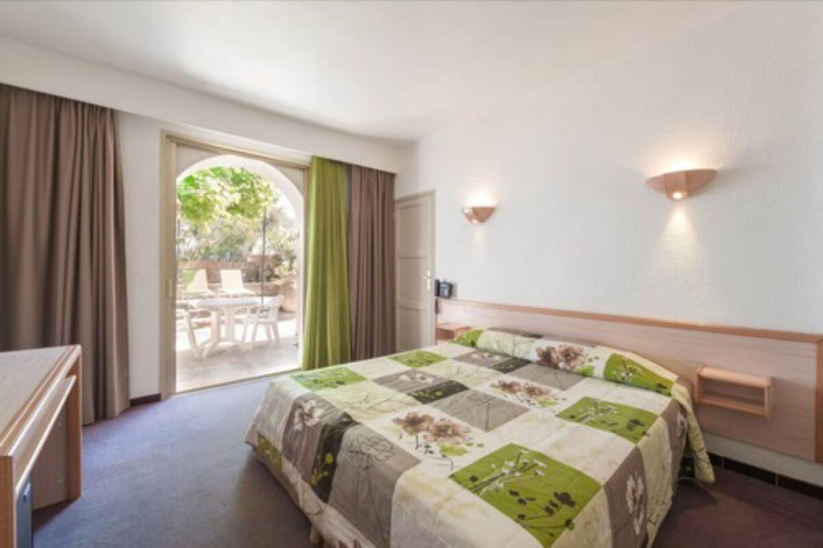 Habitación de hotel con una cama grande, un escritorio y vistas a un patio exterior.