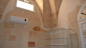 A room with stone walls, a built-in shelf, and a window with a light fixture. - Le Terrazze B&B (Manduria)