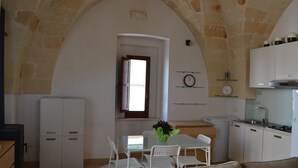 A compact kitchen with white cabinets, a dining table with chairs, and a small refrigerator. - Le Terrazze B&B (Manduria)