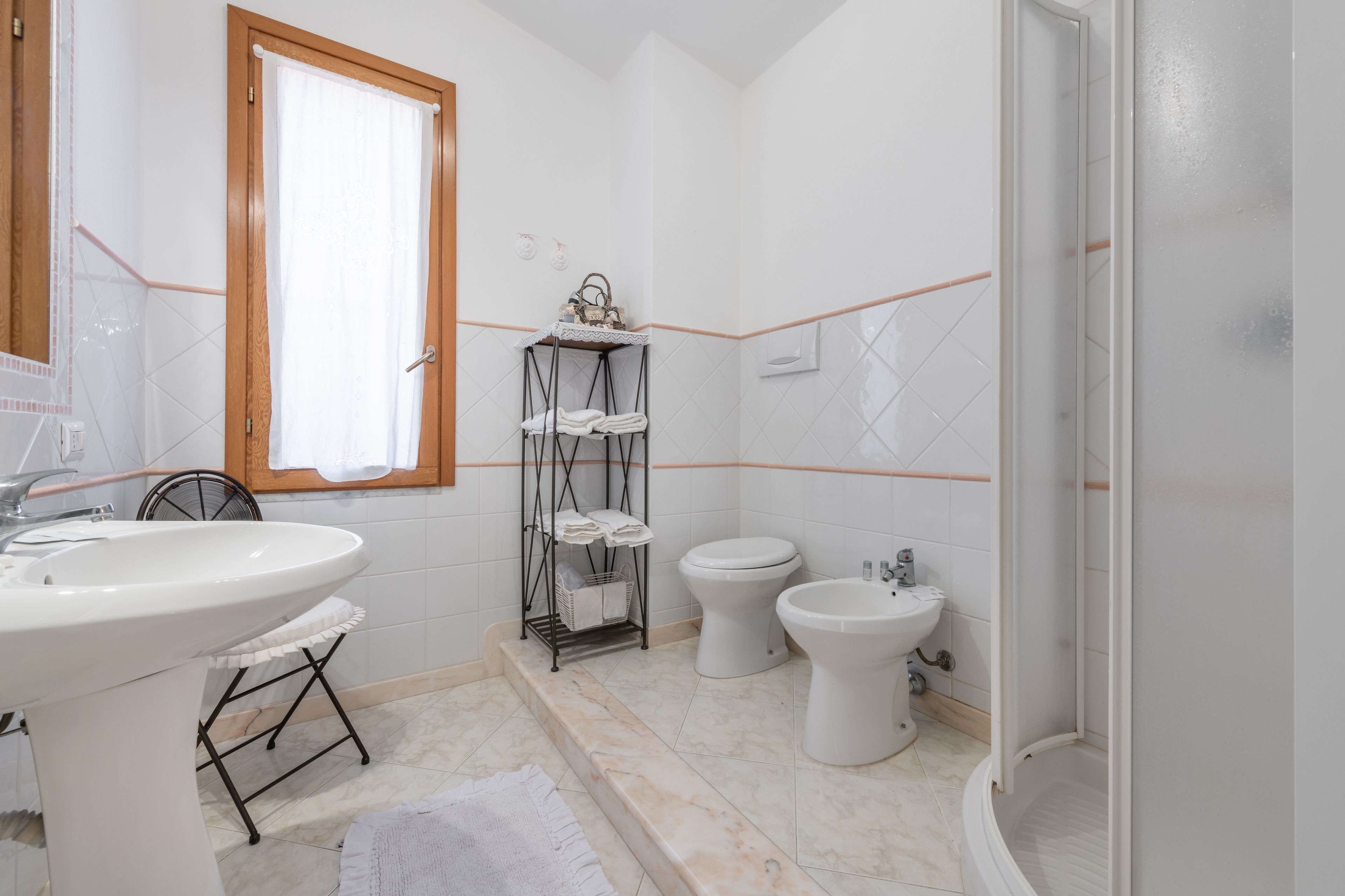 A bathroom with a sink, two toilets, a bidet, and a shower.
