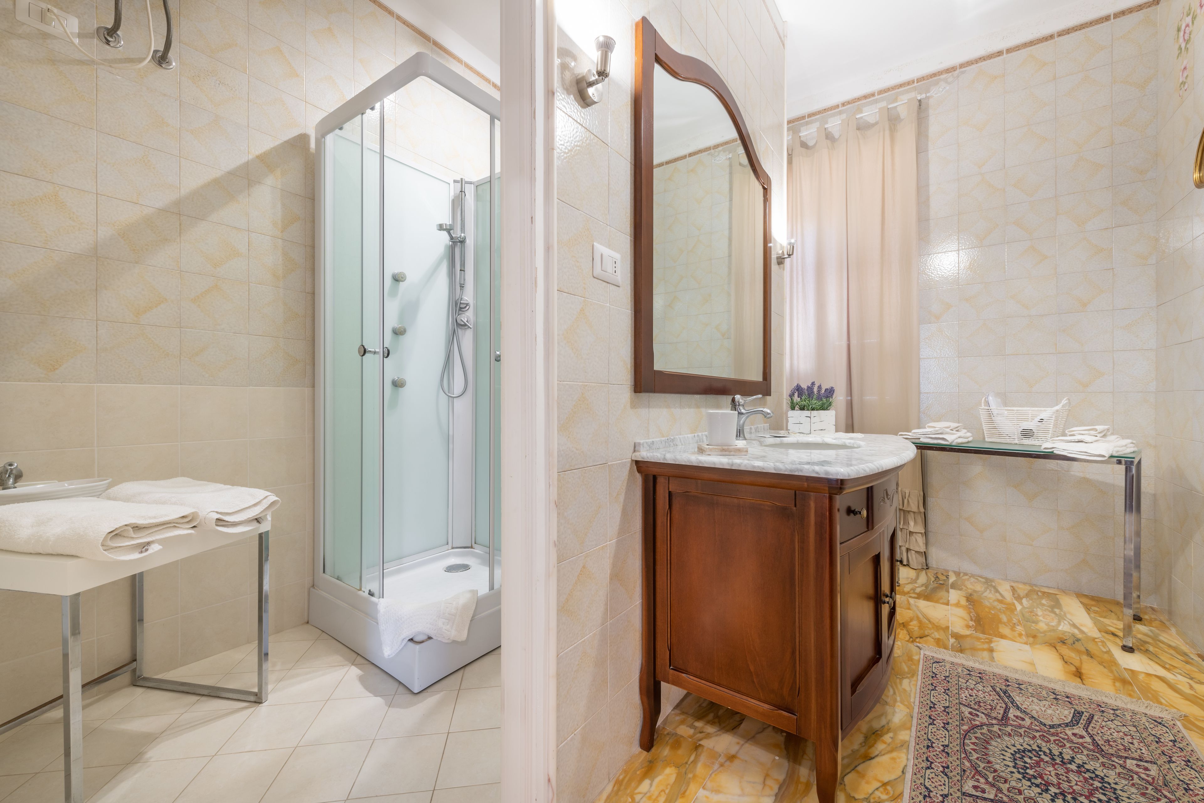Un baño con ducha, lavabo, espejo y tocador.
