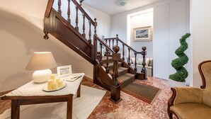 A wooden staircase with a white wall and a green plant in the corner. - Villa Iole (Carloforte)
