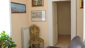 A living room with a sofa, a radiator, a chair, and framed pictures on the wall. - Come D'Incanto a Napoli (Naples)