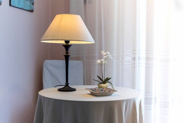 Une table avec une lampe et une petite orchidée en pot.