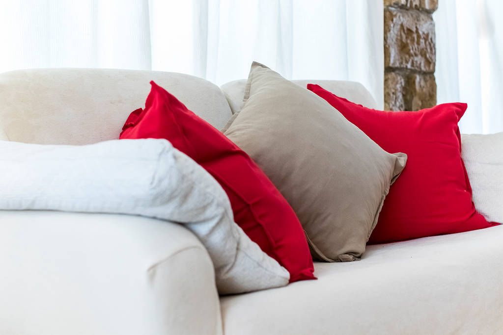 Ein weißes Sofa mit drei Kissen in verschiedenen Farben.
