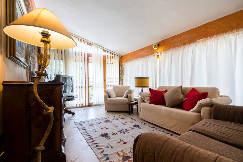 Ein Wohnzimmer mit einer Couch, Sesseln, einer Lampe und einem gemusterten Teppich.