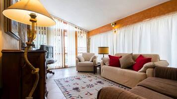 Ein Wohnzimmer mit einer Couch, Sesseln, einer Lampe und einem gemusterten Teppich.
