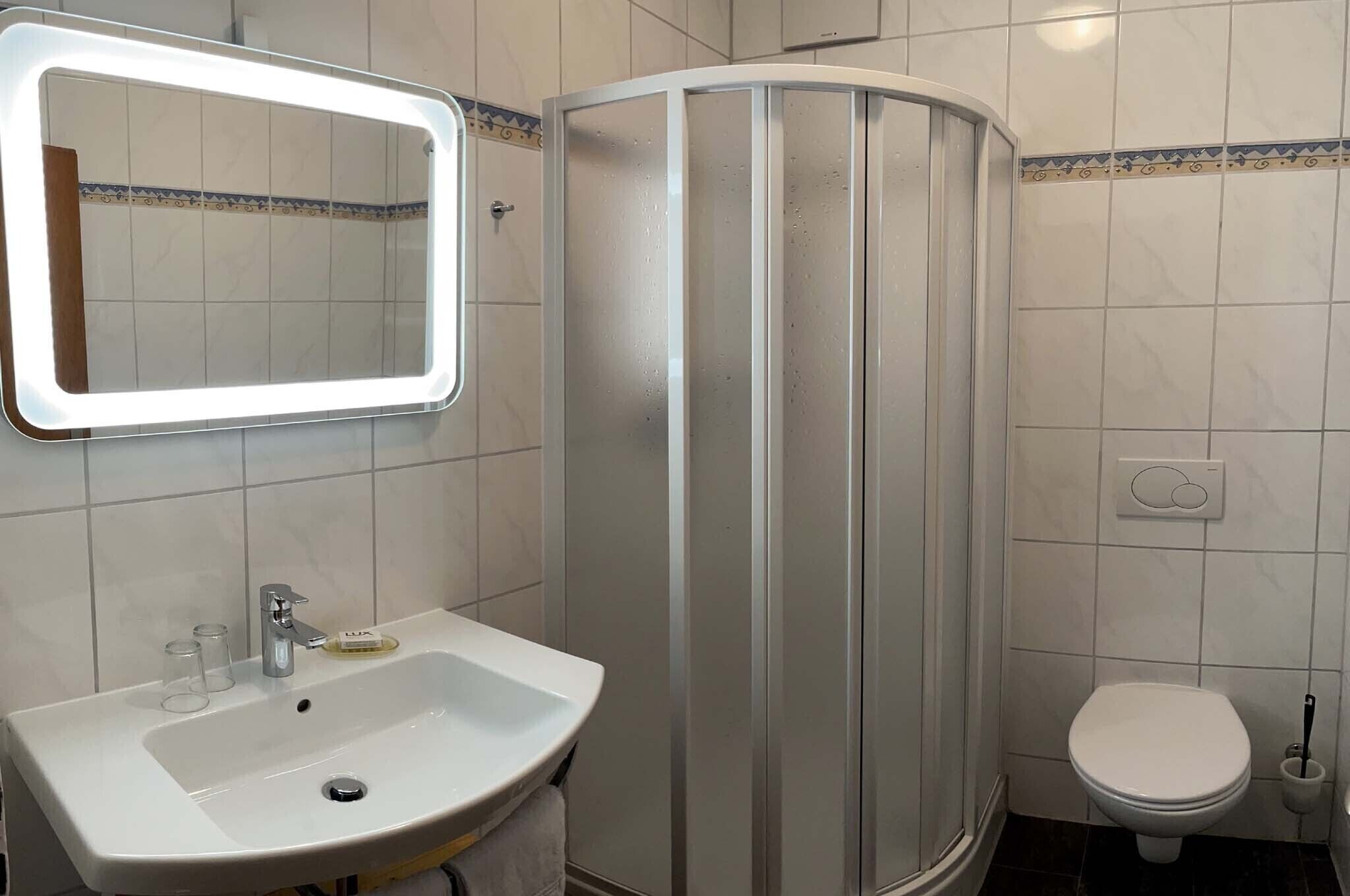 Un baño con lavamanos, espejo, ducha e inodoro.