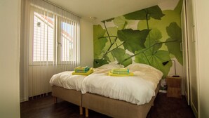 A bedroom with a bed, two pillows, a bedside table, and a wall mural. - Spitsbroek (Eede)