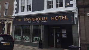 Un edificio con un letrero que indica que es el Townhouse Hotel, un café, bar y restaurante.