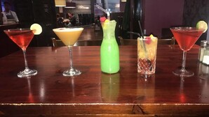 Un bar con cinco cócteles diferentes sobre una mesa de madera.