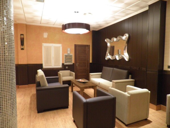 A lobby with a seating area, a reception desk, and a mirror on the wall.