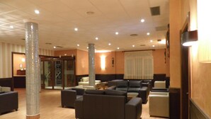 Eine Lobby mit einer zentralen Säule, einer Sitzecke und einem Empfangstresen.