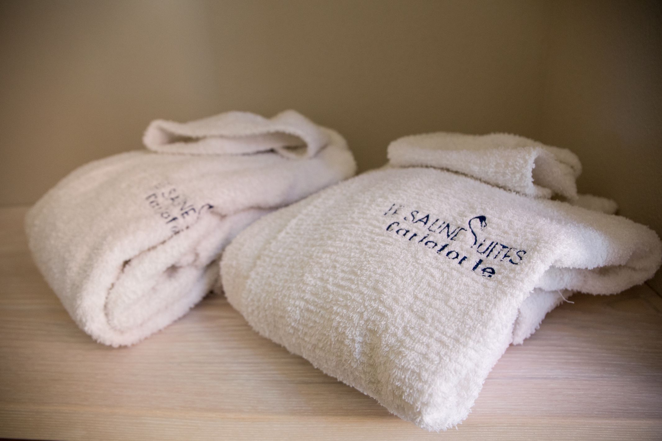 Two white towels with text on them, placed on a wooden surface.