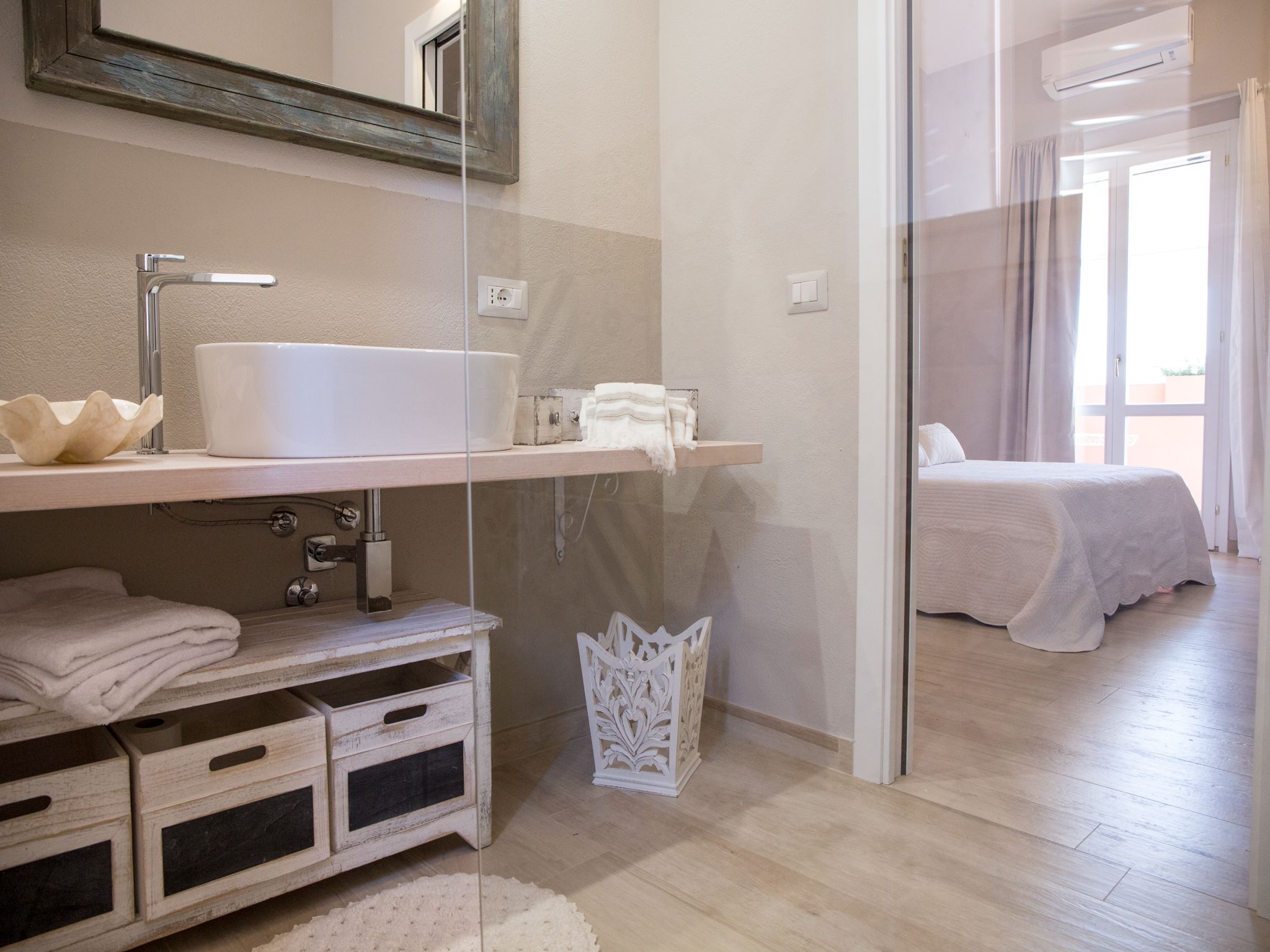 Een moderne badkamer met een grote witte wastafel, een spiegel en een douchecabine van glas.