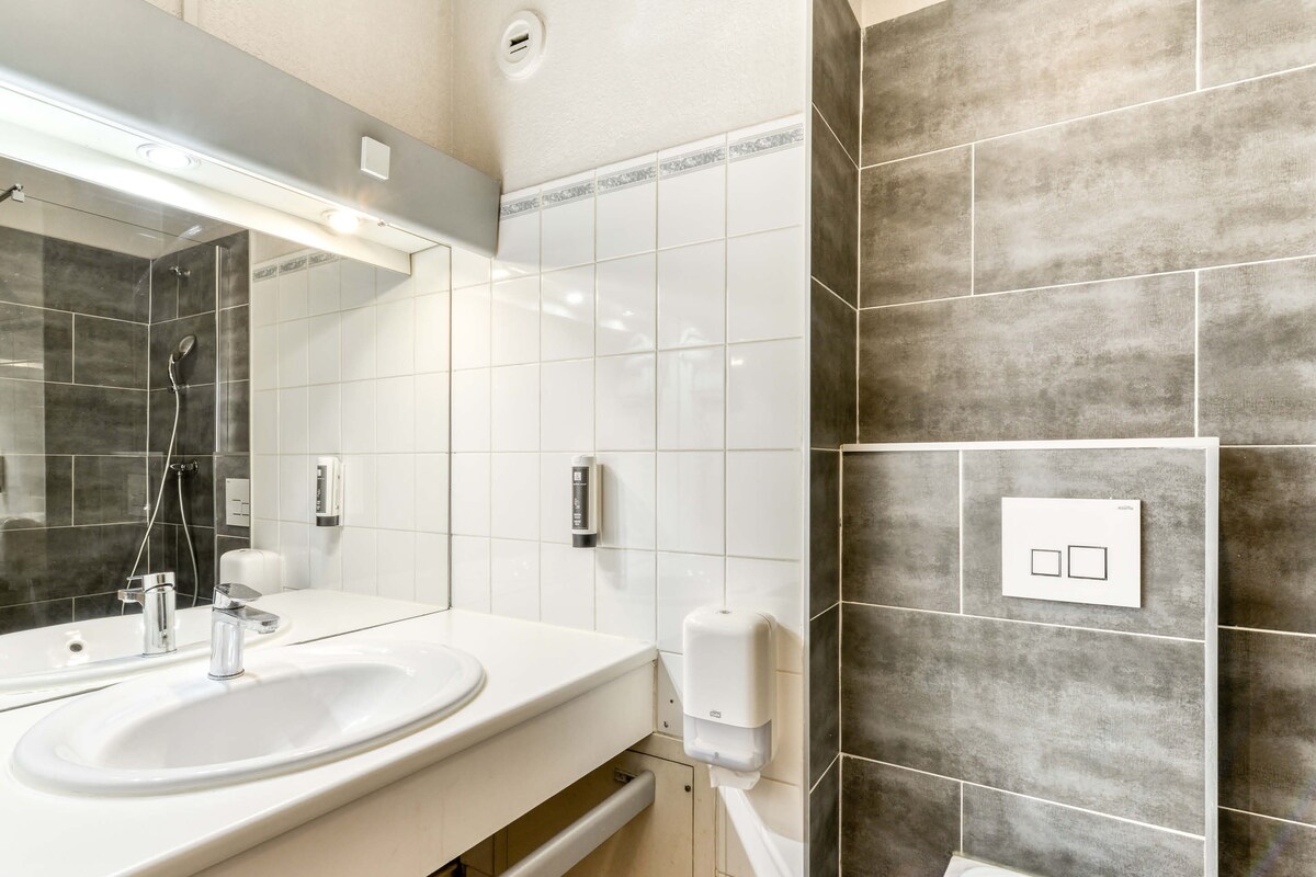 Une salle de bain moderne avec un lavabo blanc, un miroir et un espace douche.