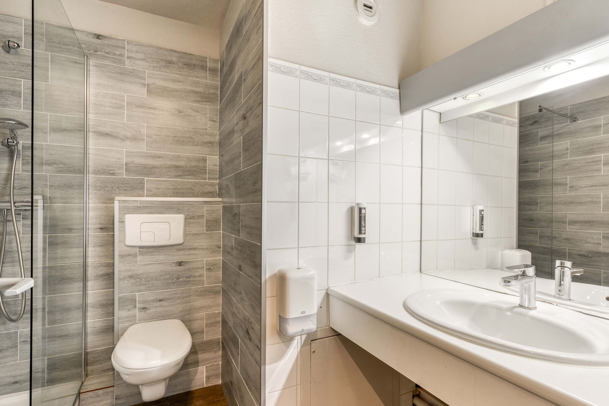 Een moderne badkamer met douche, toilet en wastafel.