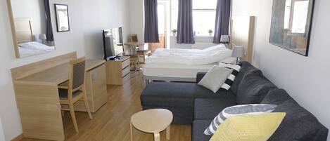 Una habitación de hotel moderna con cama, sofá, escritorio y silla.