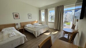 A hotel room with two beds, a dining table, and a TV. - Hótel Borgarnes (Borgarnes)