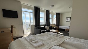 A hotel room with a large bed, a sofa, a small table, and a TV. - Hótel Borgarnes (Borgarnes)