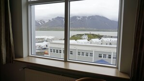 A room with a large window overlooking a body of water and mountains. - Hótel Borgarnes (Borgarnes)