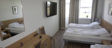 Une chambre d’hôtel avec deux lits, un bureau, une chaise, une télévision et une fenêtre avec des rideaux.