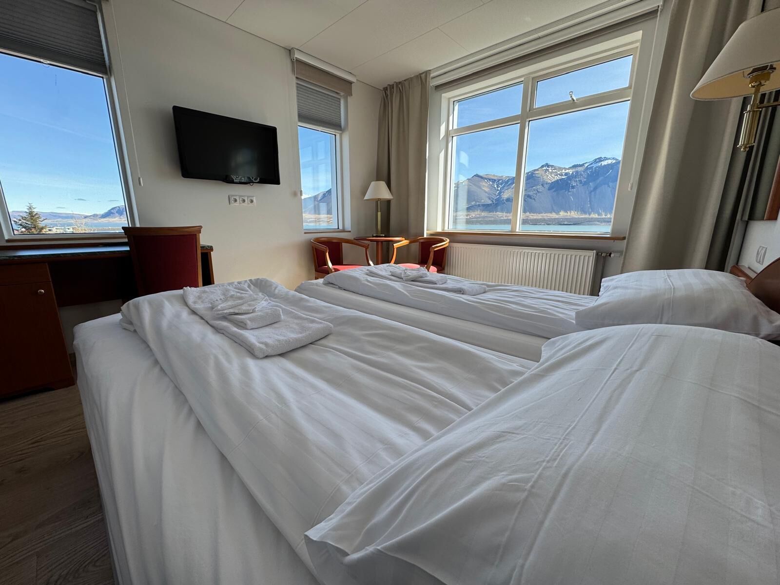 A hotel room with two beds, a TV, a desk, and a chair.