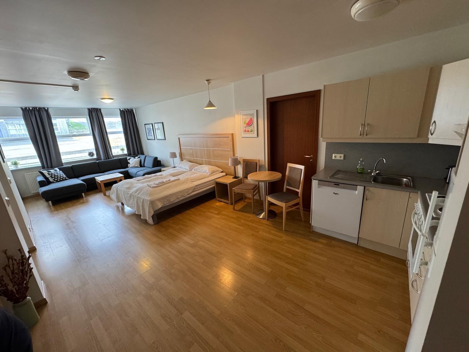Una habitación de hotel moderna con una cama, un sofá, una mesa de comedor y una kitchenette.