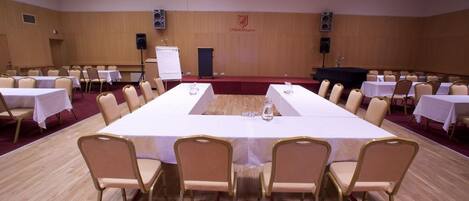 Un salón de conferencias con una larga mesa, sillas, un atril y una pizarra.