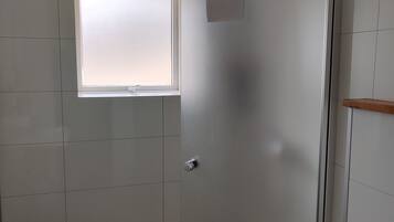 A bathroom with a shower, a sink, and a window.