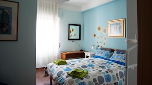 A bedroom with a bed, a desk, a chair, a lamp, and a framed picture on the wall. - Alma B&B (Crotone)